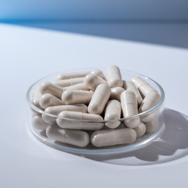 Cápsulas de color blanco del suplemento Skin Vit A+ mostradas de cerca para apreciar su tamaño y textura